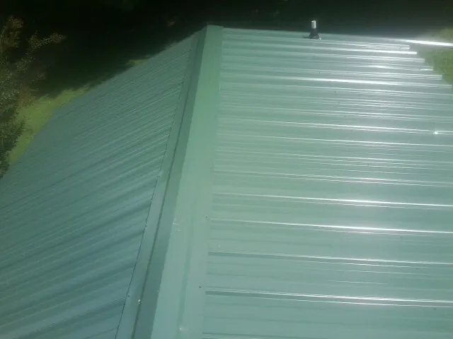 New green metal panels meeting at the ridge of a roof — Flat Roof Repair work by our crew in Brandon
